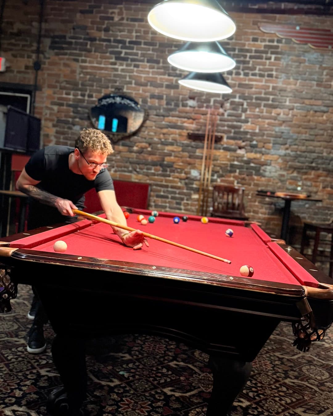 A guest lines up a pool shot while others talk nearby